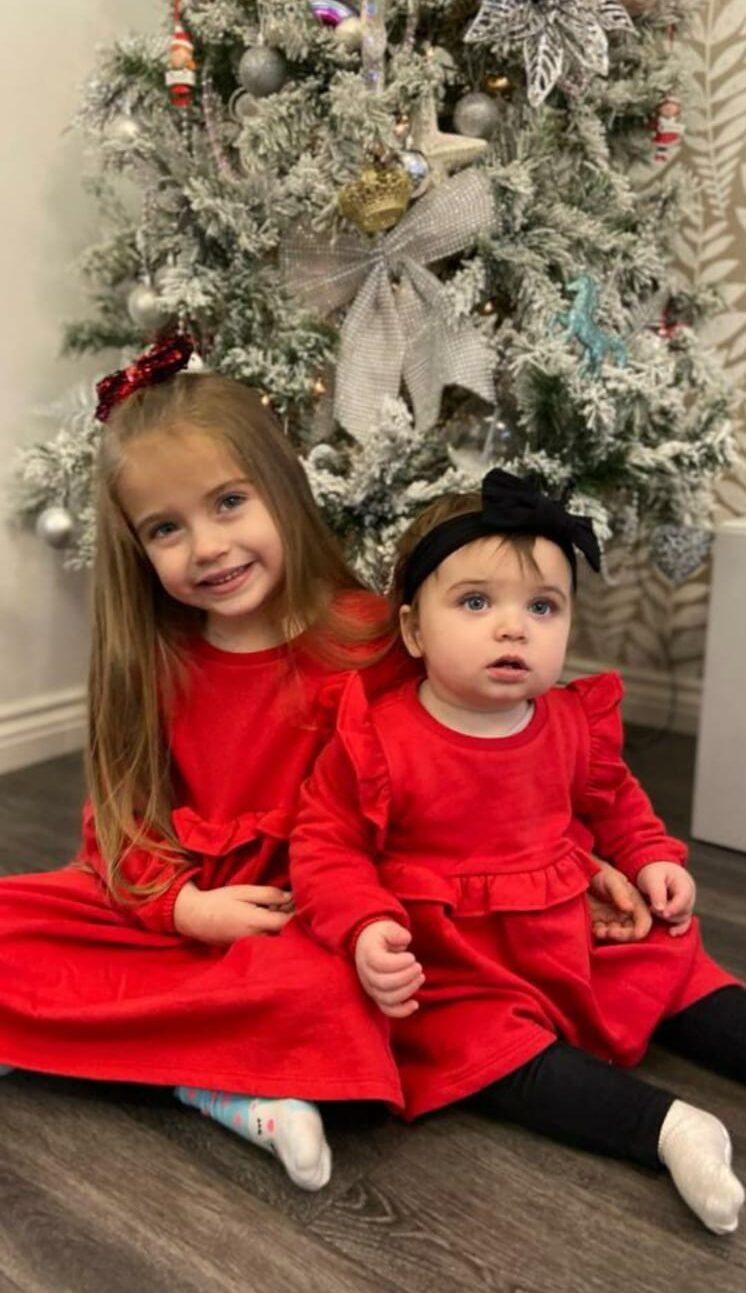 Living kidney recipient Daisy-May and her sister Lily under a Christmas tree