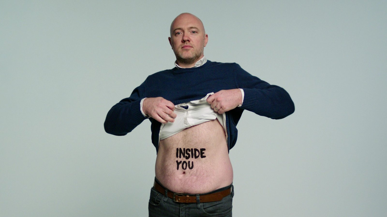 Living kidney donor James lifting his top to reveal the words 'inside you' on his stomach