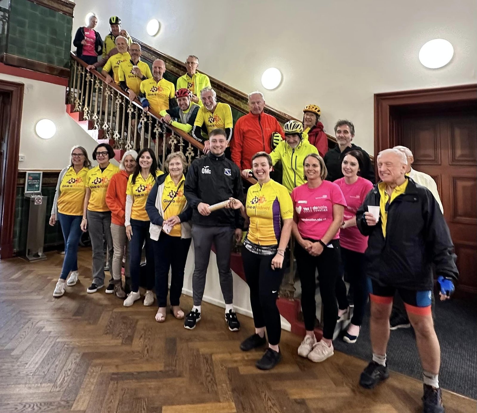 Living kidney donor Dennis and his cycling support team in a grand hallway, all looking at the camera and smiling