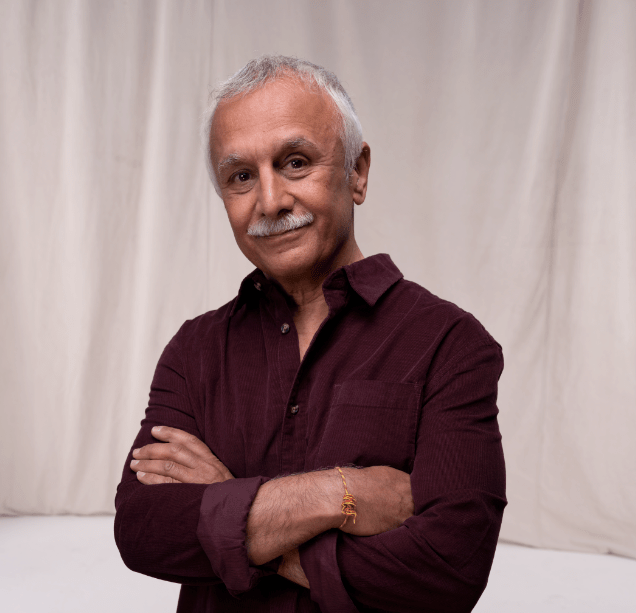 Image of non-directed kidney donor Sanjiv smiling at the camera with his arms crossed