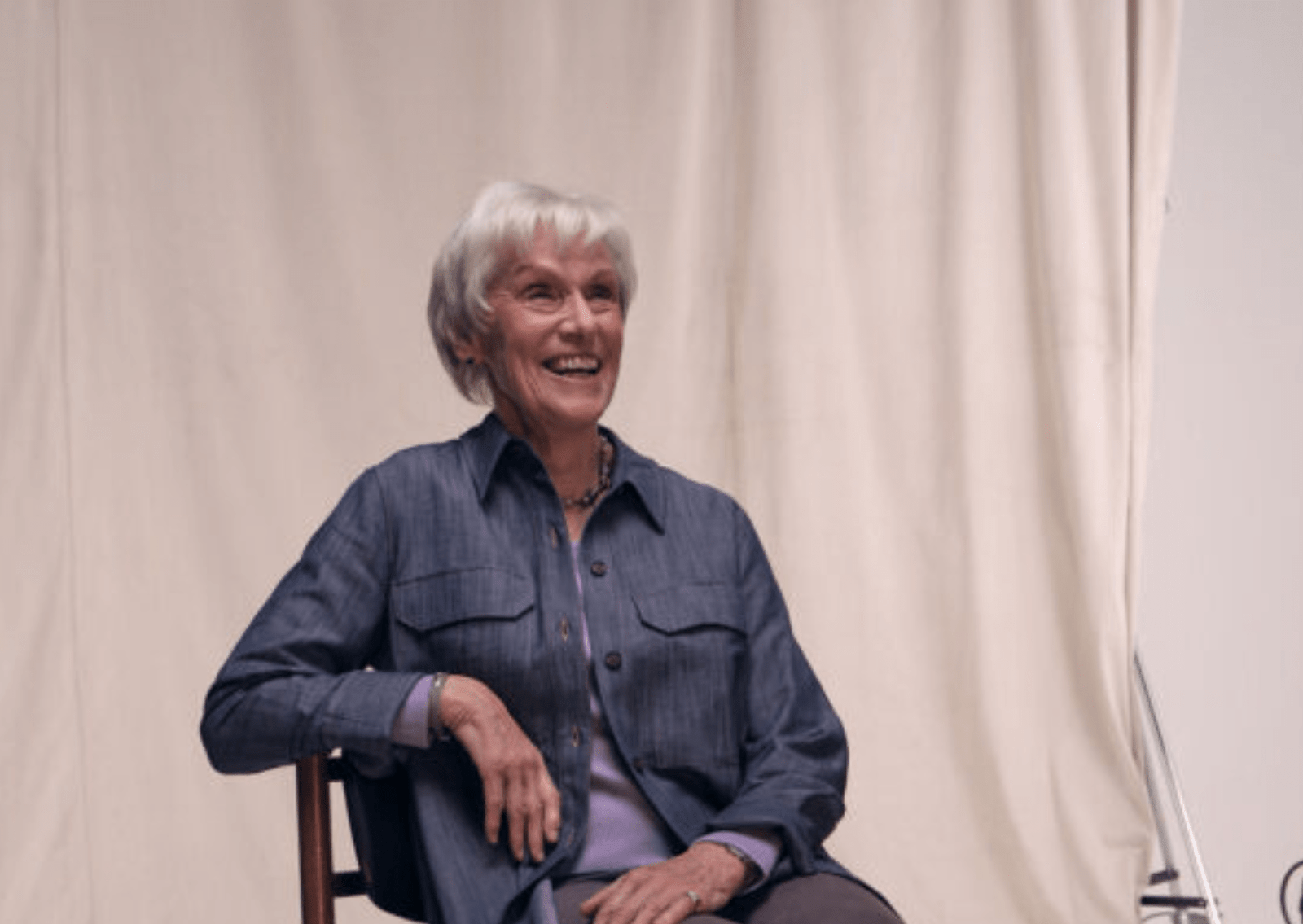 Image of living kidney donor Celia leaning back against a wooden chair and smiling.