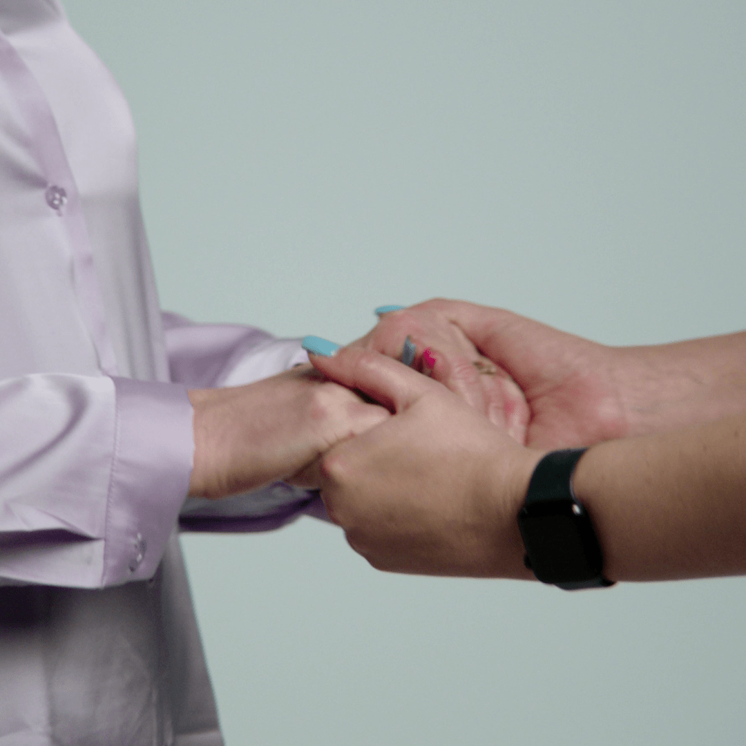 A close up image of two people holding each other's hands.